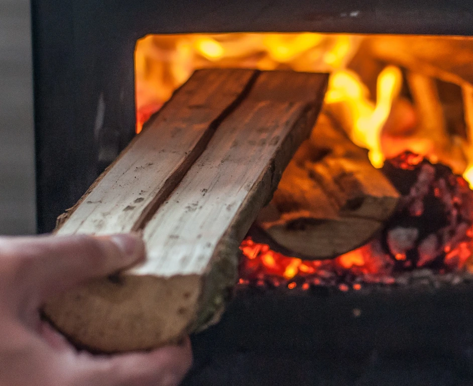Man putting log to wood burning stove