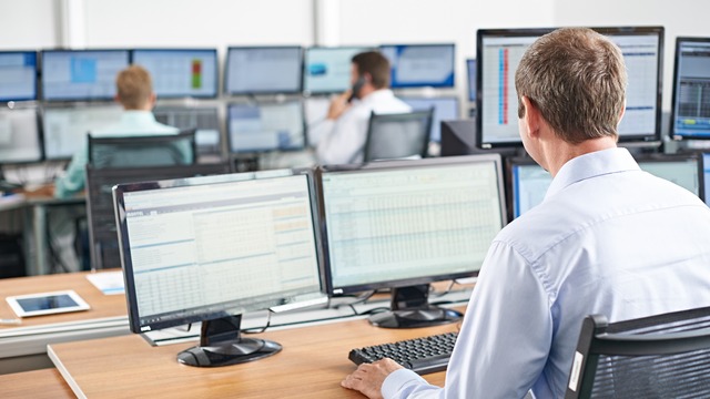 man sitting in office in front of screens