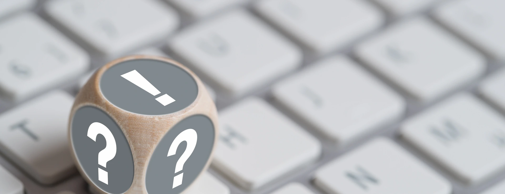 Würfel mit Fragezeichen auf den Seiten und Ausrufezeichen oben auf einer Tastatur
