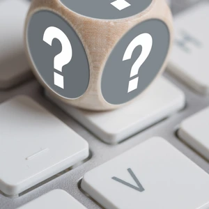 Würfel mit Fragezeichen auf den Seiten und Ausrufezeichen oben auf einer Tastatur