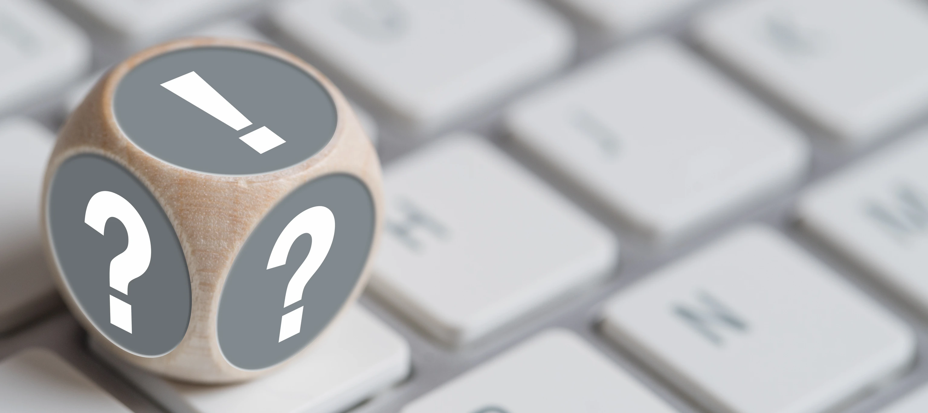 Würfel mit Fragezeichen auf den Seiten und Ausrufezeichen oben auf einer Tastatur