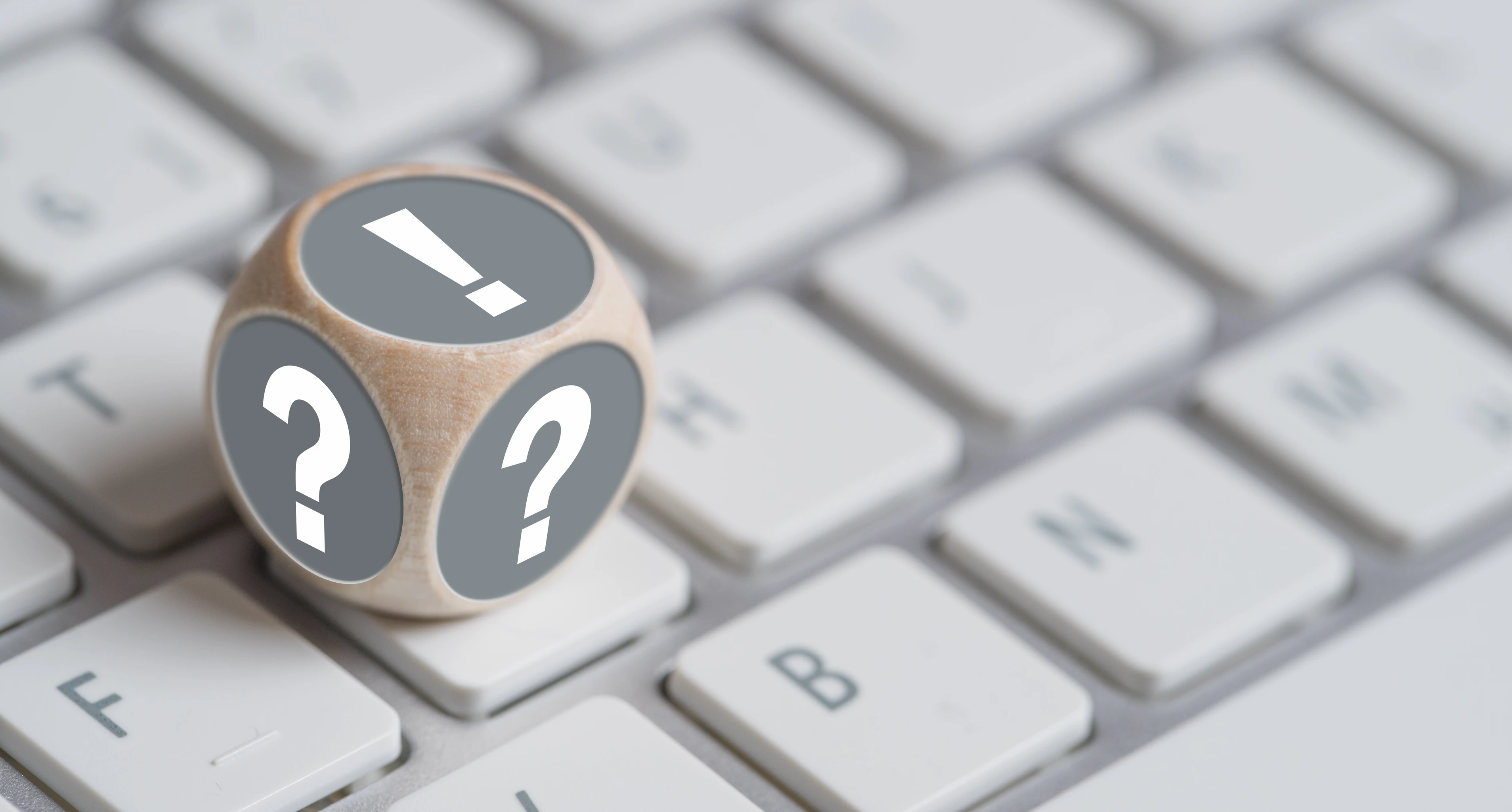 Würfel mit Fragezeichen auf den Seiten und Ausrufezeichen oben auf einer Tastatur