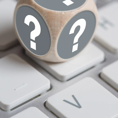 Würfel mit Fragezeichen auf den Seiten und Ausrufezeichen oben auf einer Tastatur