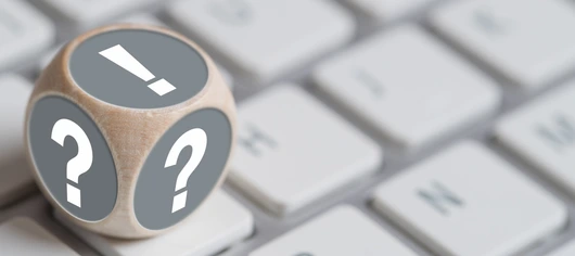 Würfel mit Fragezeichen auf den Seiten und Ausrufezeichen oben auf einer Tastatur