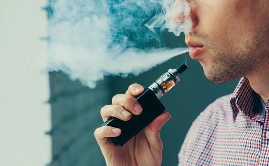 Close up on a man exhaling vapor from an electronic cigarette