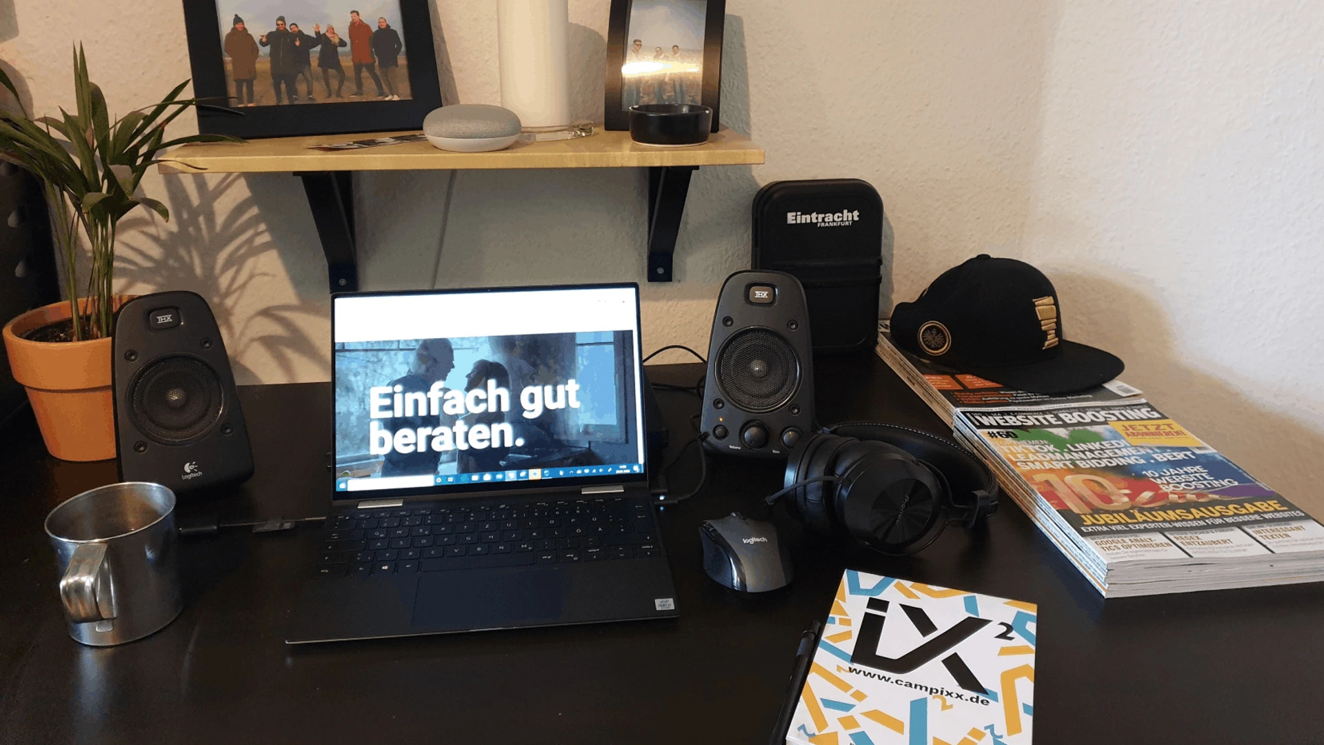 Homeoffice mit Laptop, Bildschirm zeigt Einfach gut beraten, Lautsprecher, Kopfhörer und Tasse auf PALMBERG-Schreibtisch