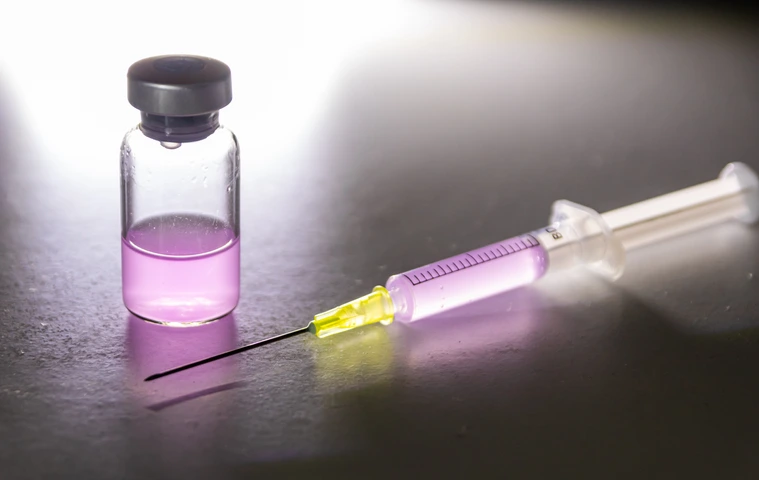 Leuchtende Spritze mit pinkfarbenem Heilmittel aus einer medizinischen Ampulle zur Therapie von Patienten mit Impfstoff und neuartigen Wirkstoffen