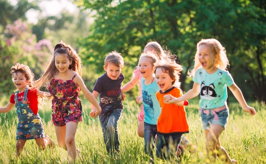 Large group of kids, friends boys and girls running in the park on sunny summer day in casual clothes
