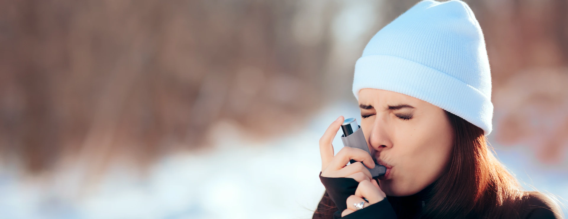 Frau inhaliert im Winter mit Asthmaspray