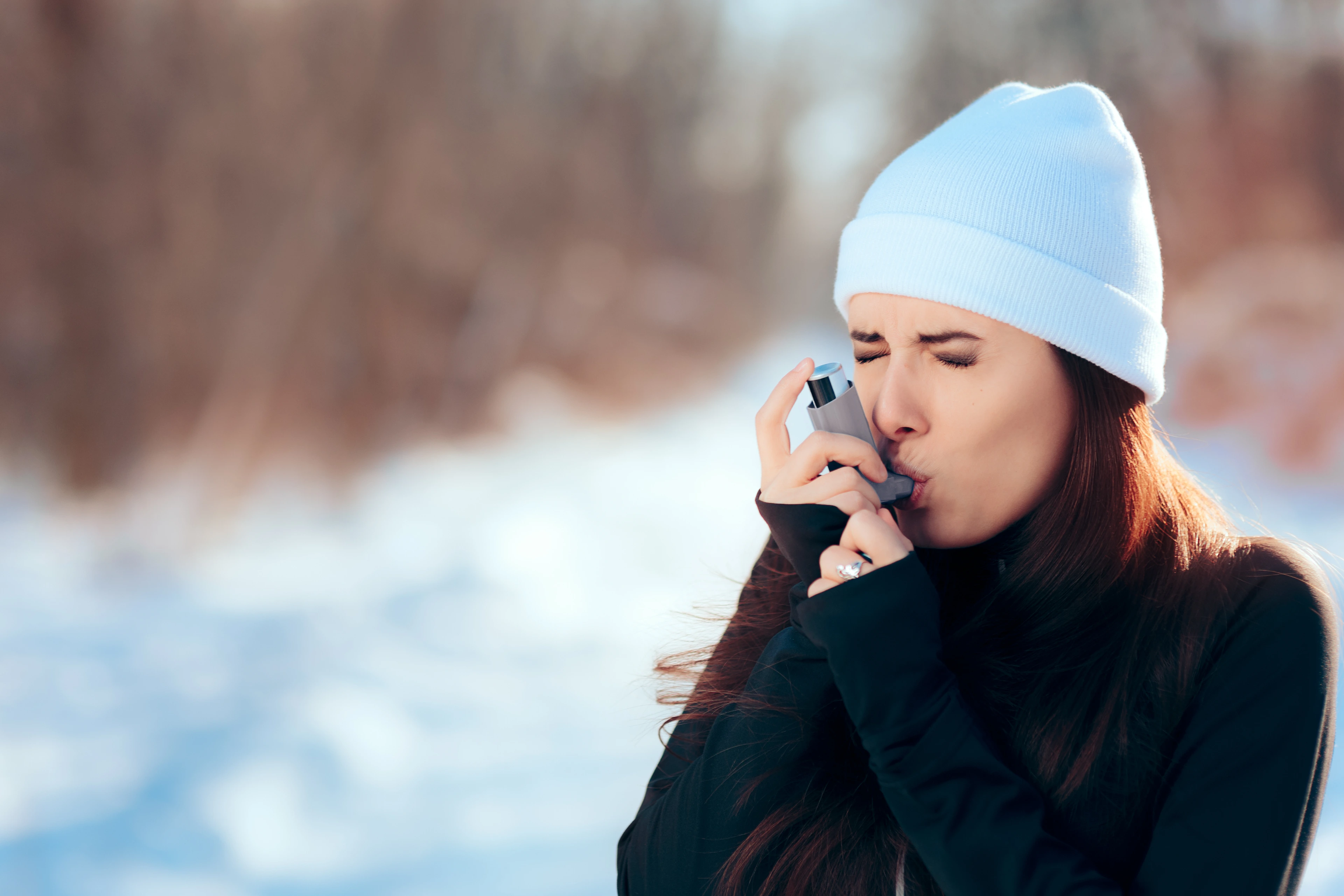 Frau inhaliert im Winter mit Asthmaspray