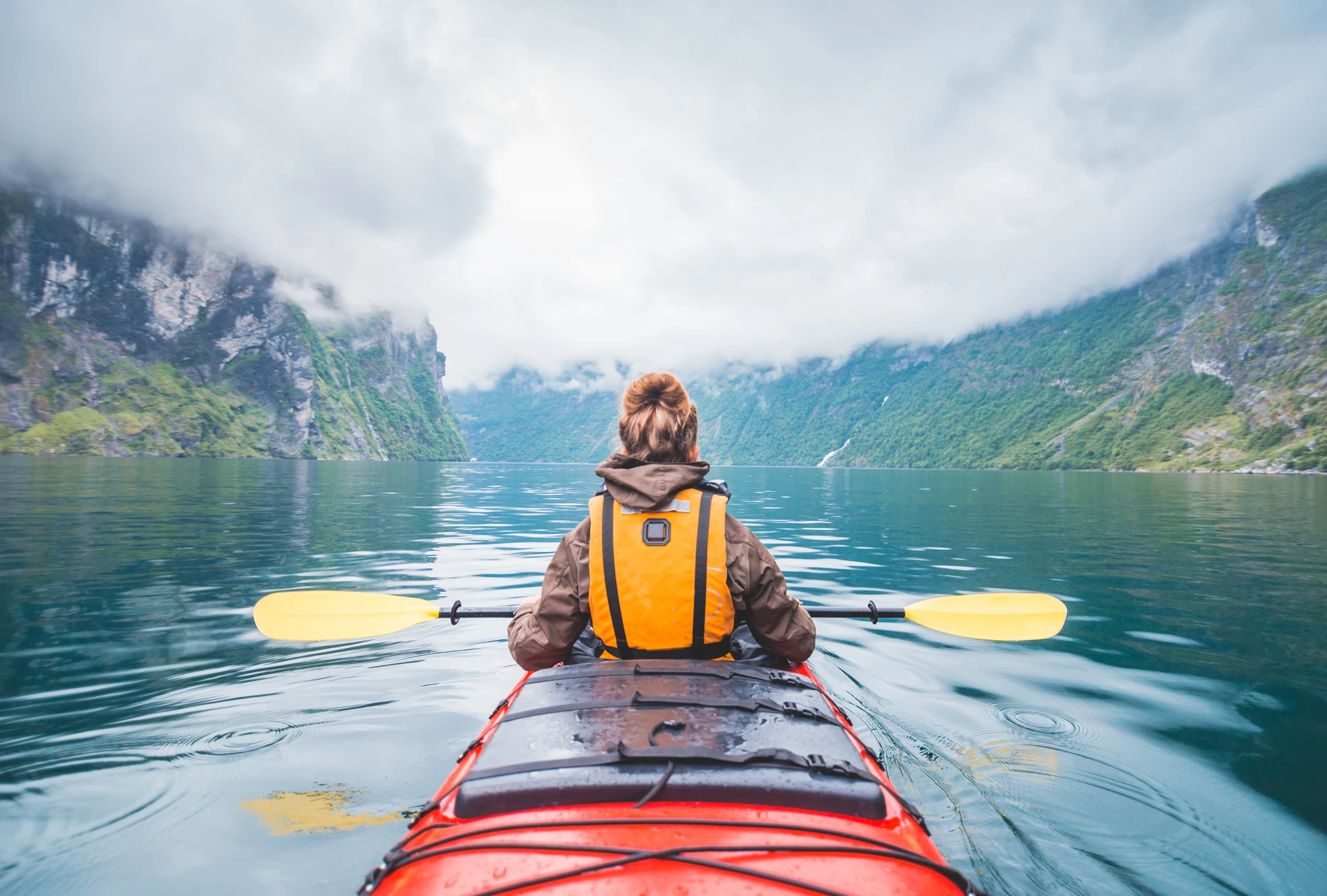 Woman kayaking in Geiranger fjord in Norway.