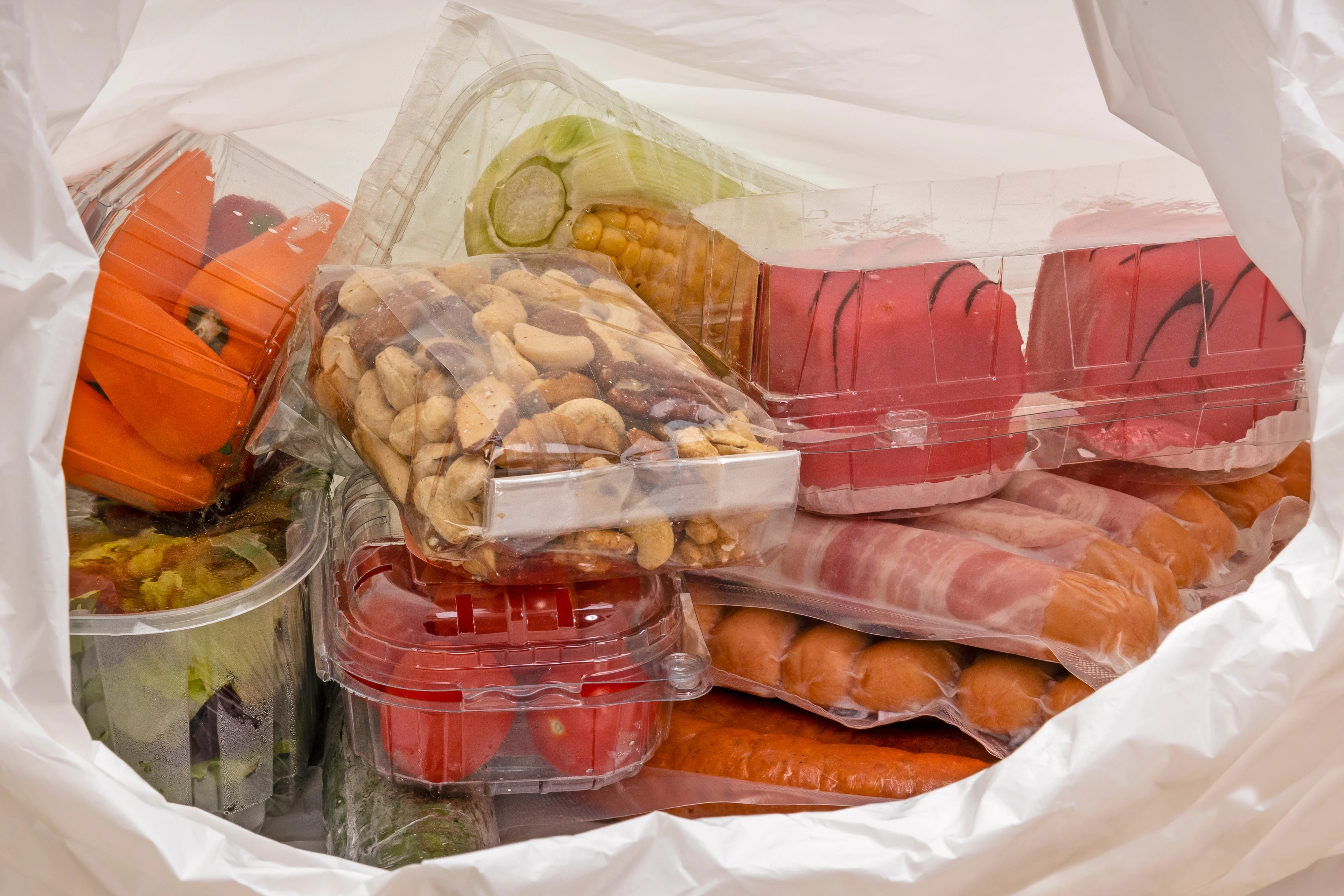 Plastiaksackerl mit Lebensmittel in Sichtverpackung aus Plastik.