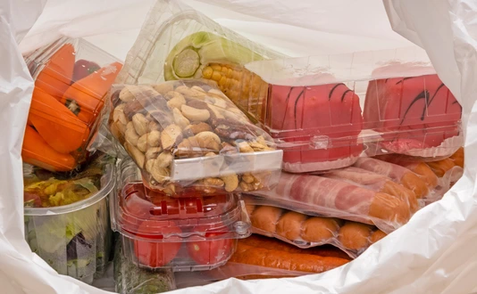Plastiaksackerl mit Lebensmittel in Sichtverpackung aus Plastik.