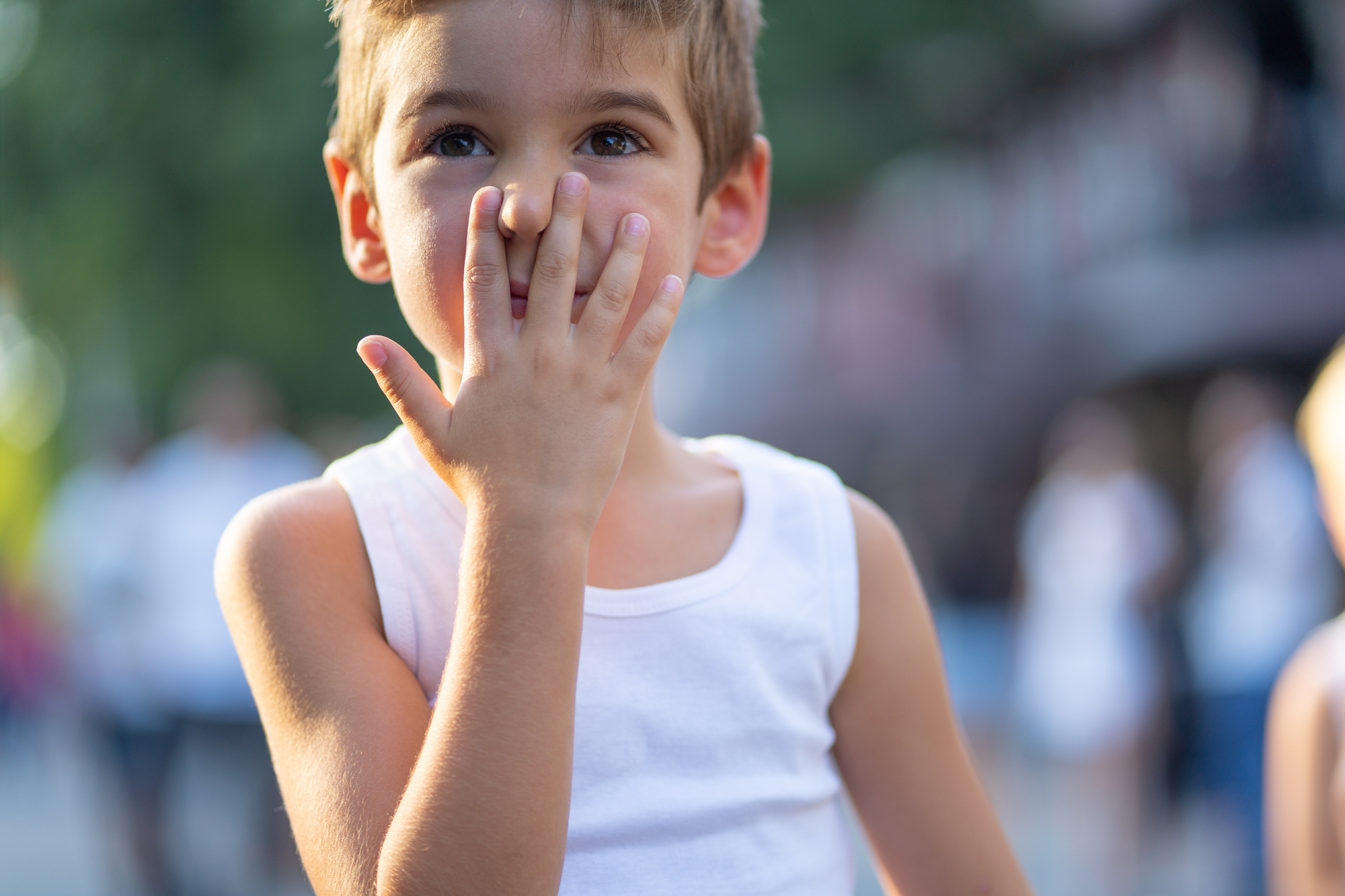 grimacing little boy outdoors in summer