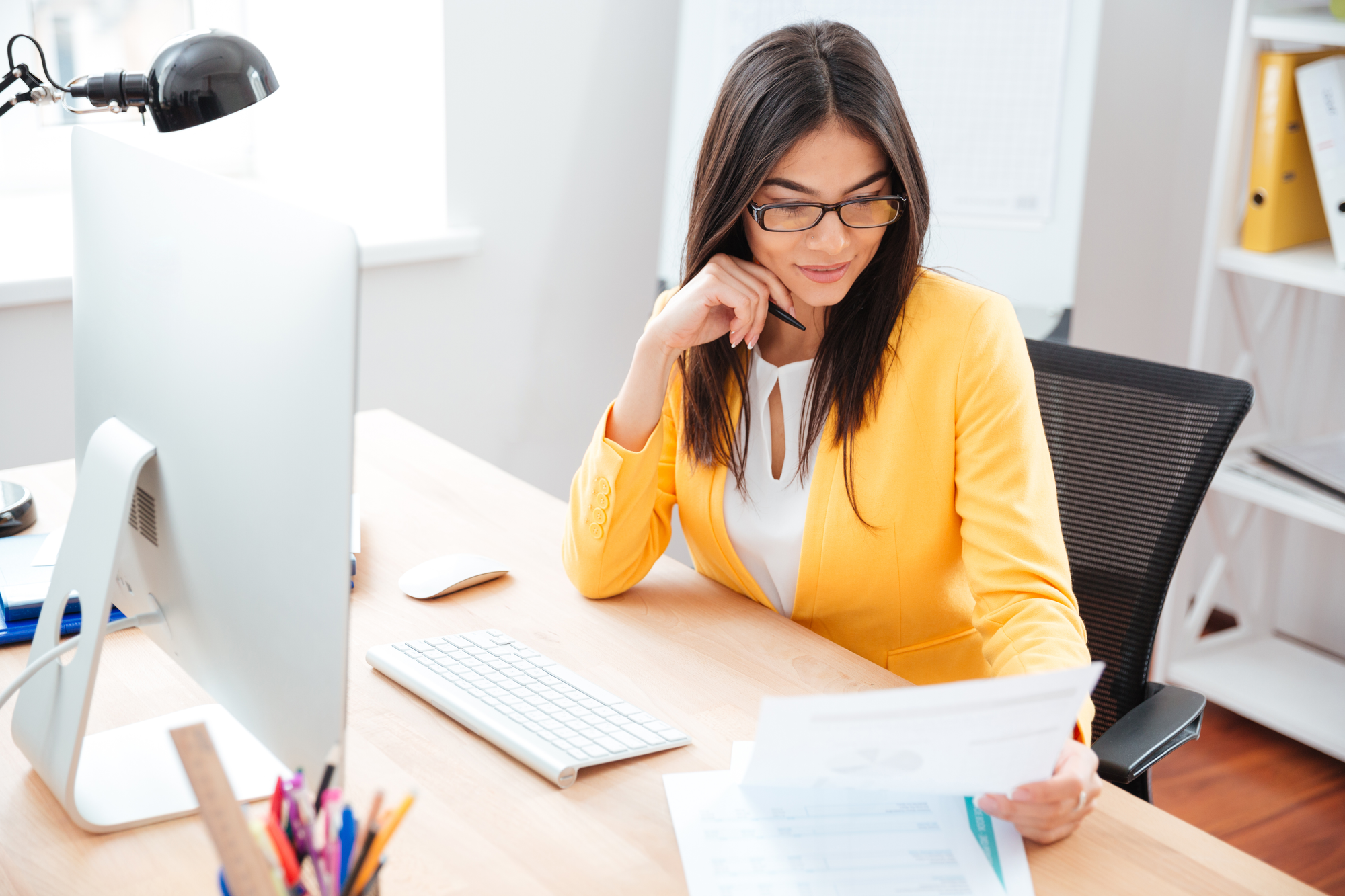 Businesswoman,Reading,Paper,At,Her,Workplace,In,Office