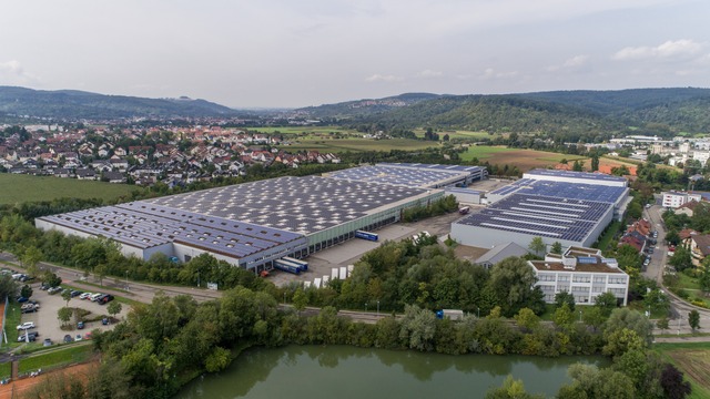 large facility with rooftop PV and village in the background