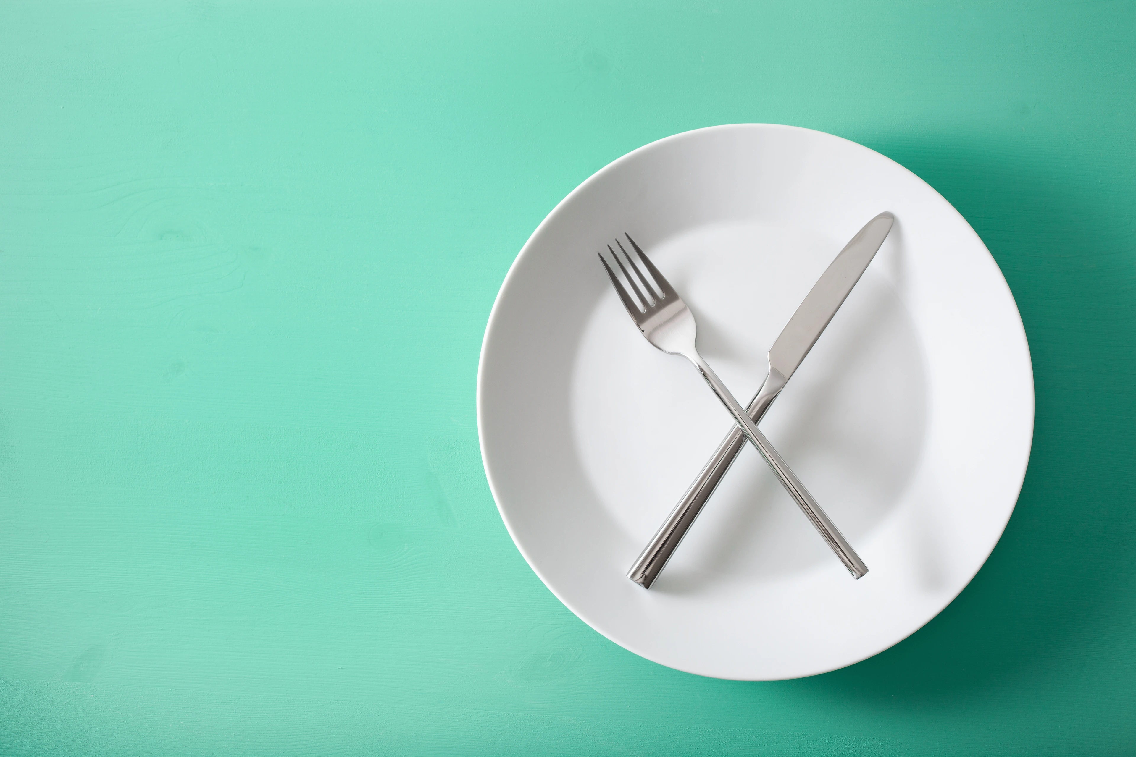 concept of intermittent fasting and ketogenic diet, weight loss. fork and knife crossed on a plate