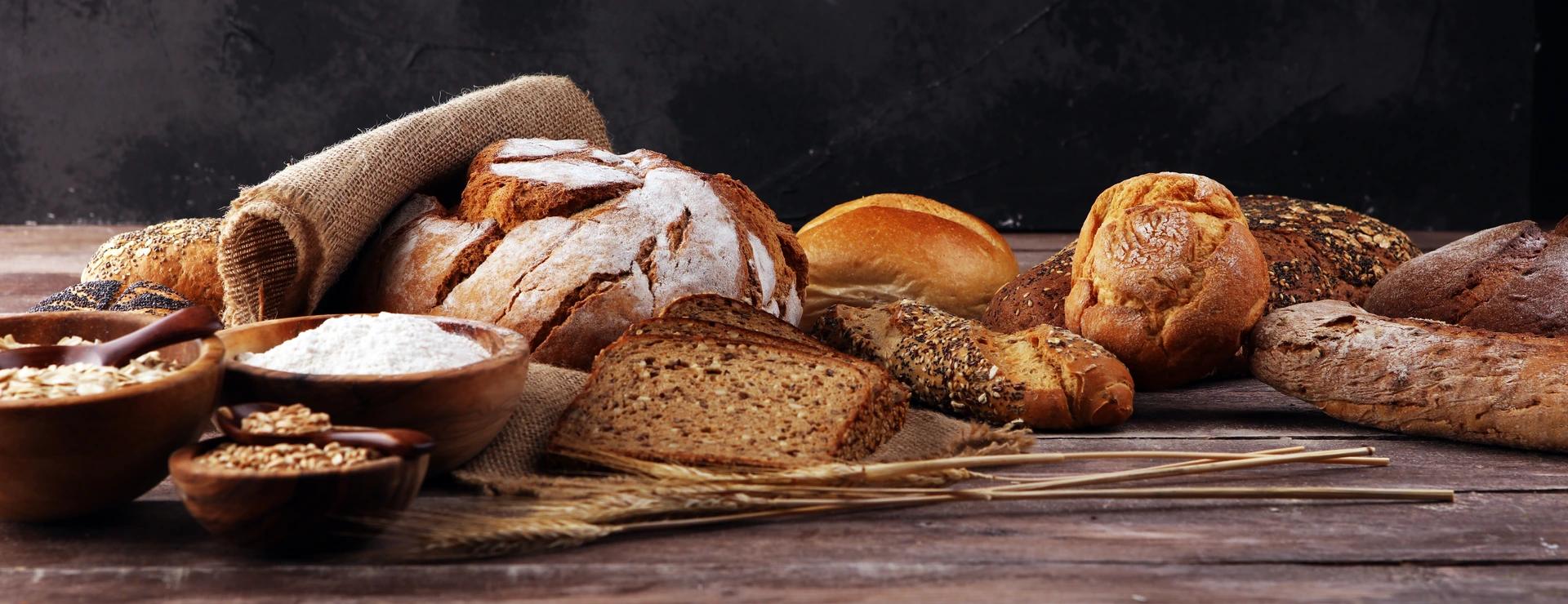 Assortment of baked bread and bread rolls on table background