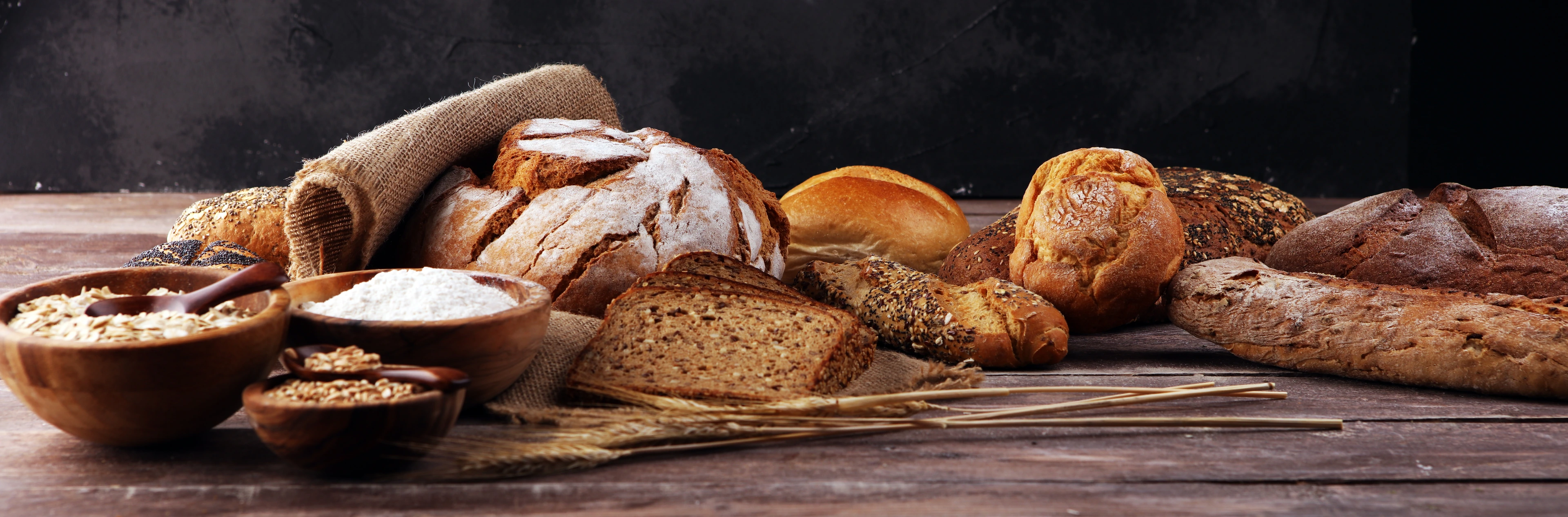 Assortment of baked bread and bread rolls on table background