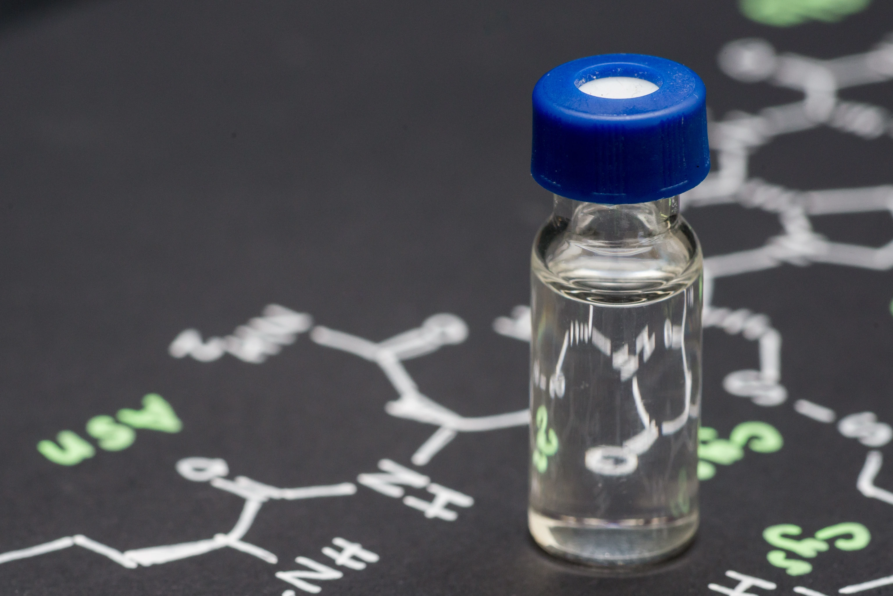 close-up blue cap sample vial on paper with formula