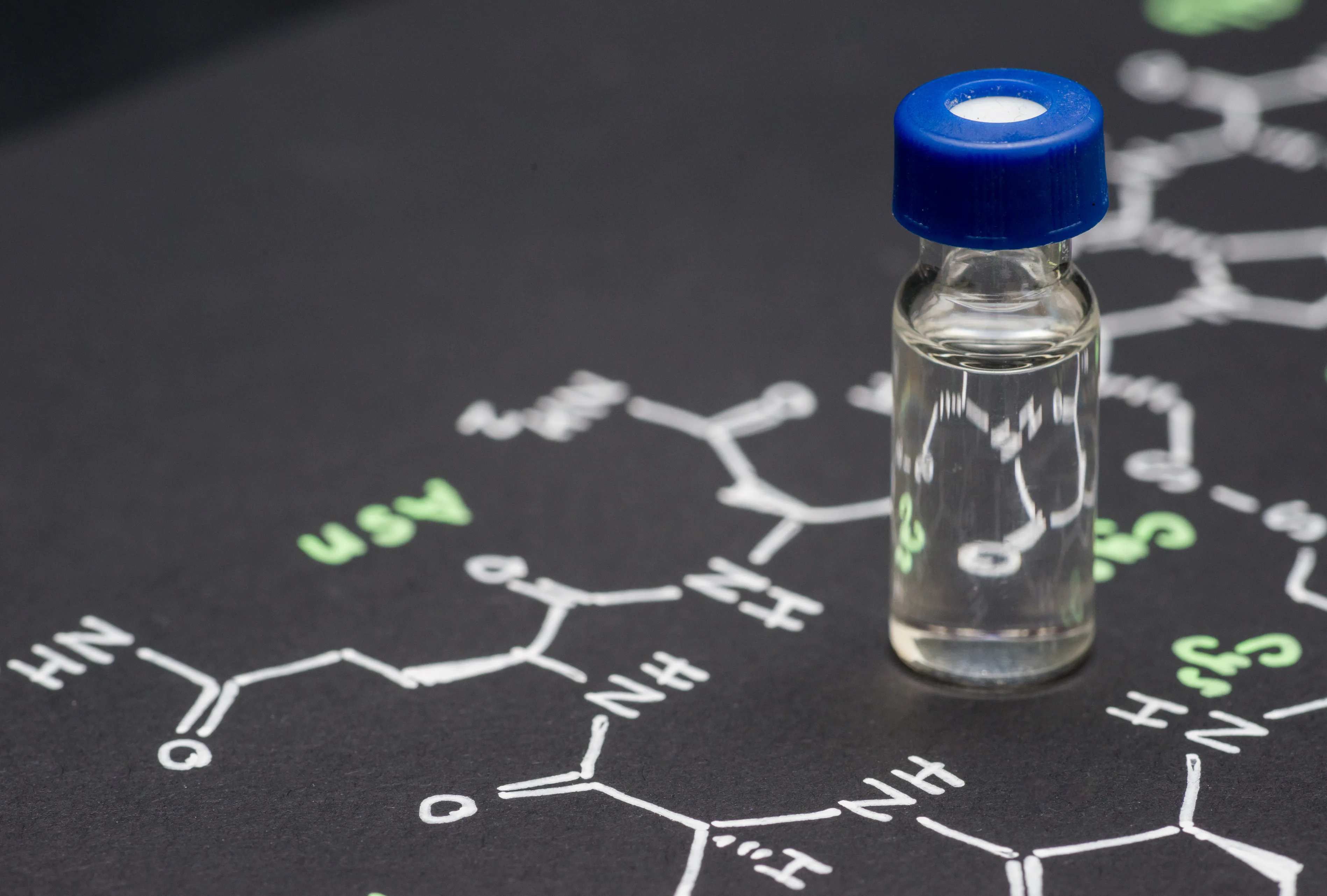 Close-up blue cap sample vial on paper with chemical formula of Oxytocin (love hormone)