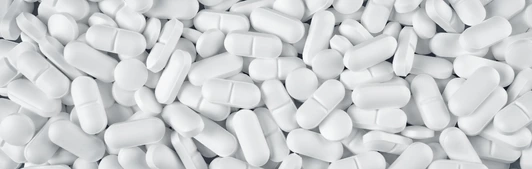 White pills spilled on blue wooden background
