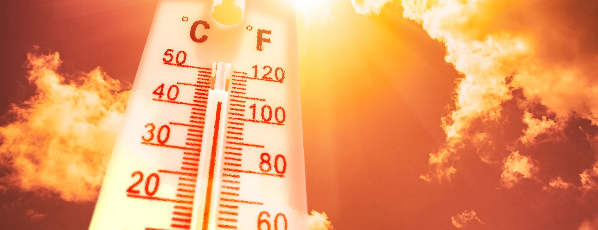 Thermometer in front of a sky with sun and clouds