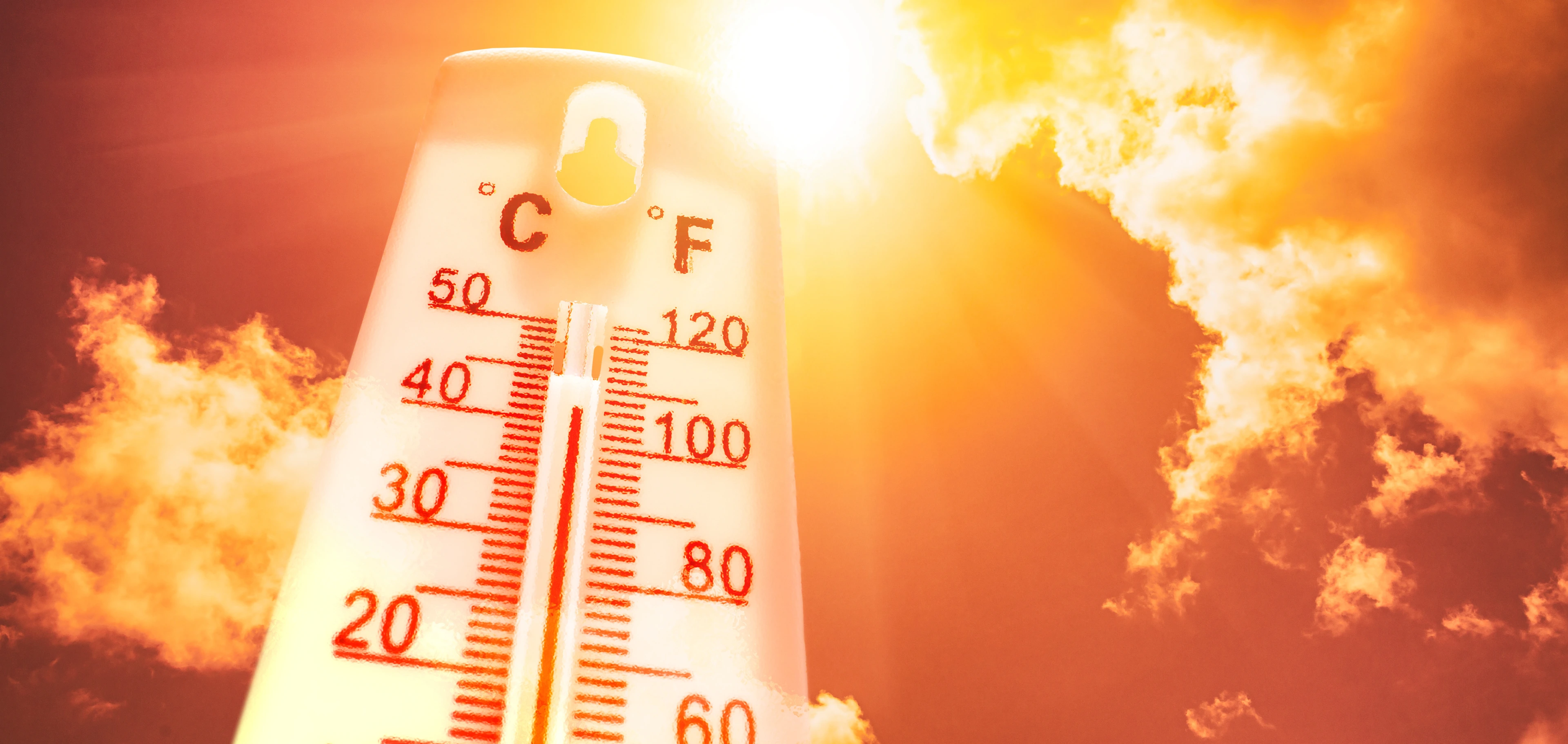 Thermometer in front of a sky with sun and clouds