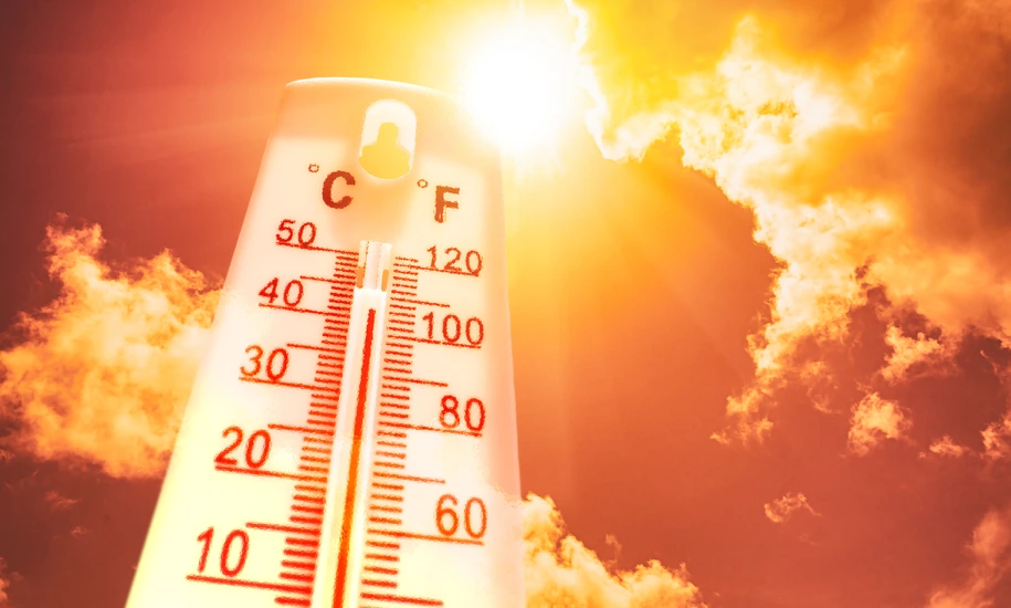 Thermometer in front of a sky with sun and clouds