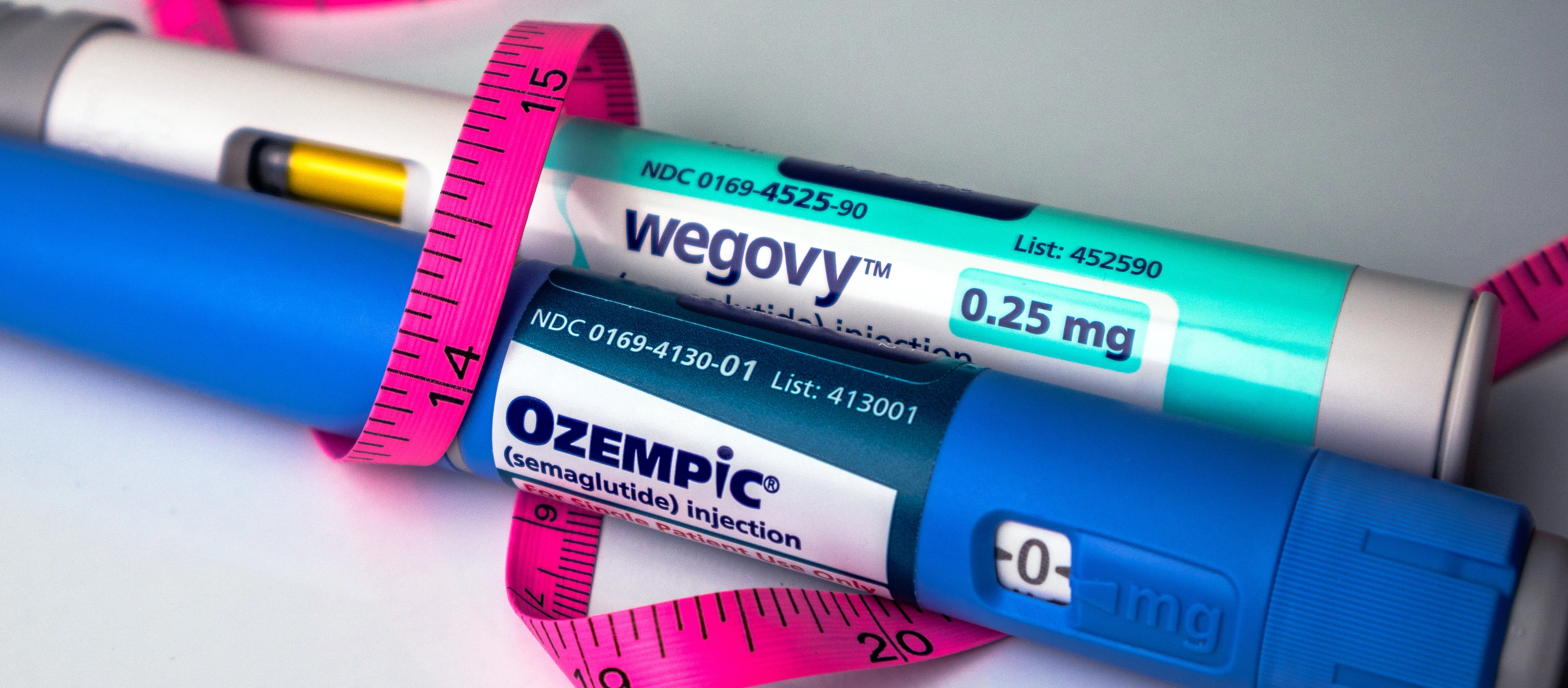 Ozempic and Wegovy semaglutide pens with pink tape measure