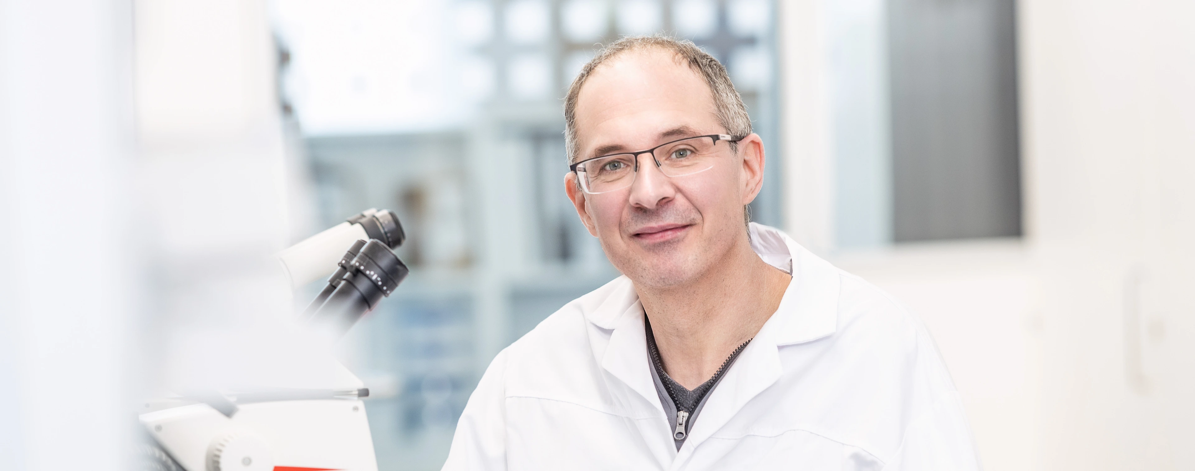 Prof. Timo Müller neben einem Mikroskop 