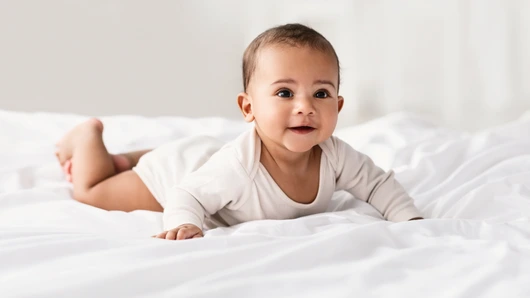 Cute little African American baby lying on bed at home