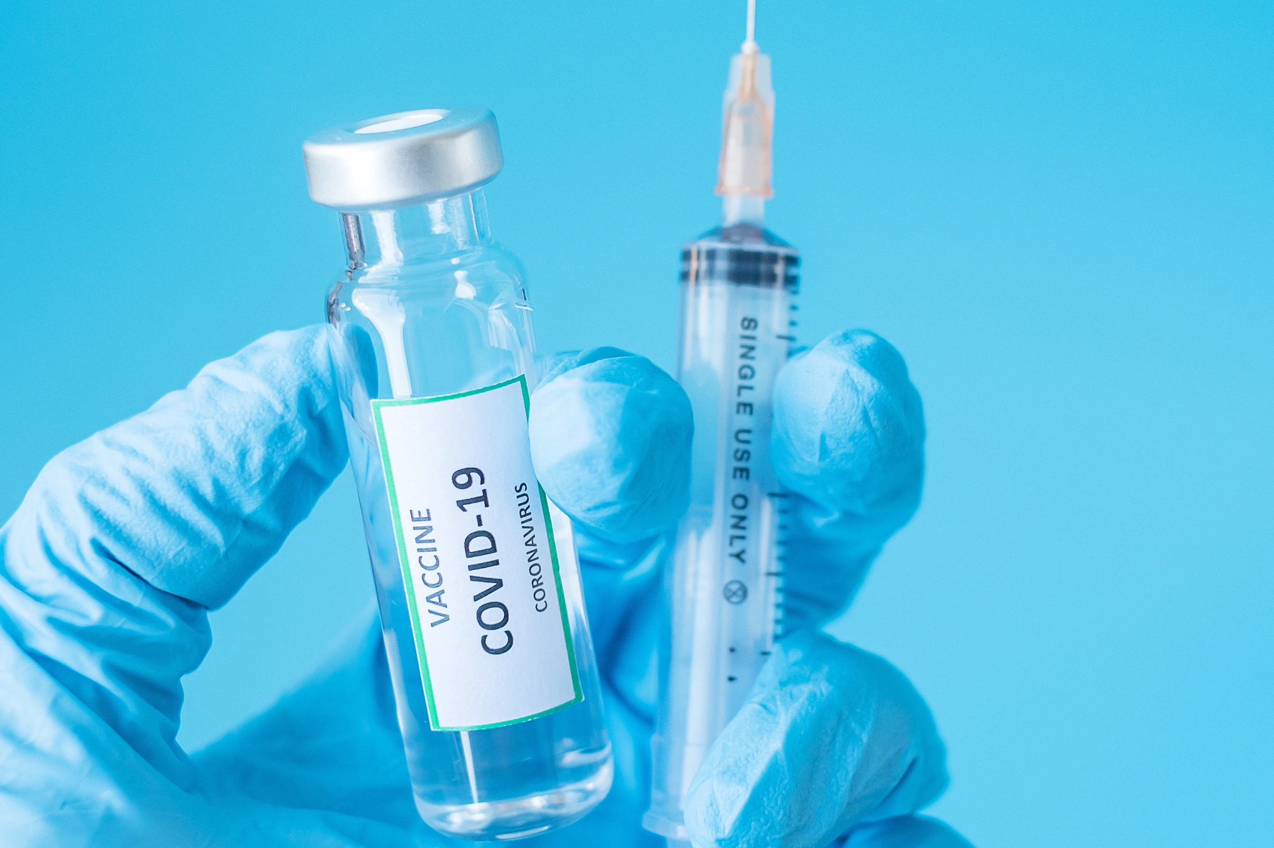 COVID-19 Vaccine vial and injection Needle Syringe against Coronavirus infection in hand of doctor with Nitrile Glove in hospital laboratory. Medical, health, Vaccination and immunization concept