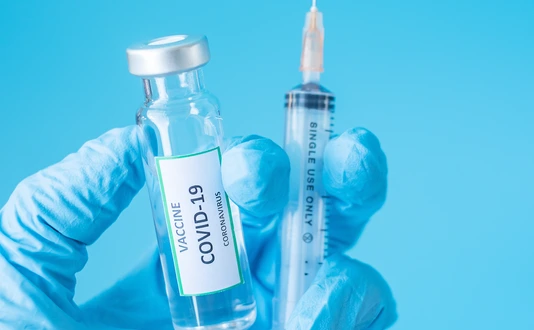 COVID-19 Vaccine vial and injection Needle Syringe against Coronavirus infection in hand of doctor with Nitrile Glove in hospital laboratory. Medical, health, Vaccination and immunization concept