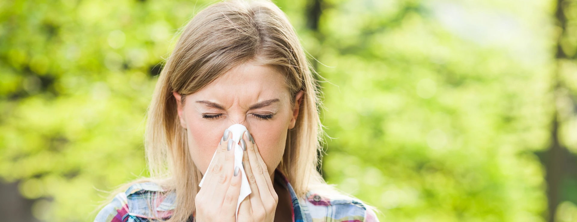 Woman with allergy symptom blowing nose