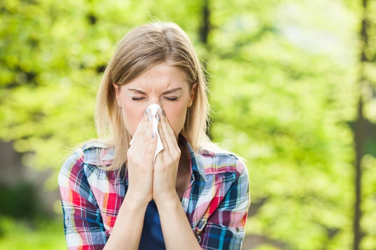 Woman with allergy symptom blowing nose