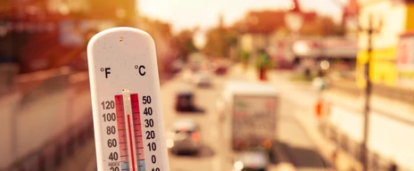 Thermometer in front of cars and traffic during heatwave in Montreal.