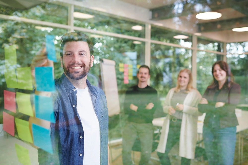 Agiles Arbeiten junges Team mit Postit bei Scrum Projekt